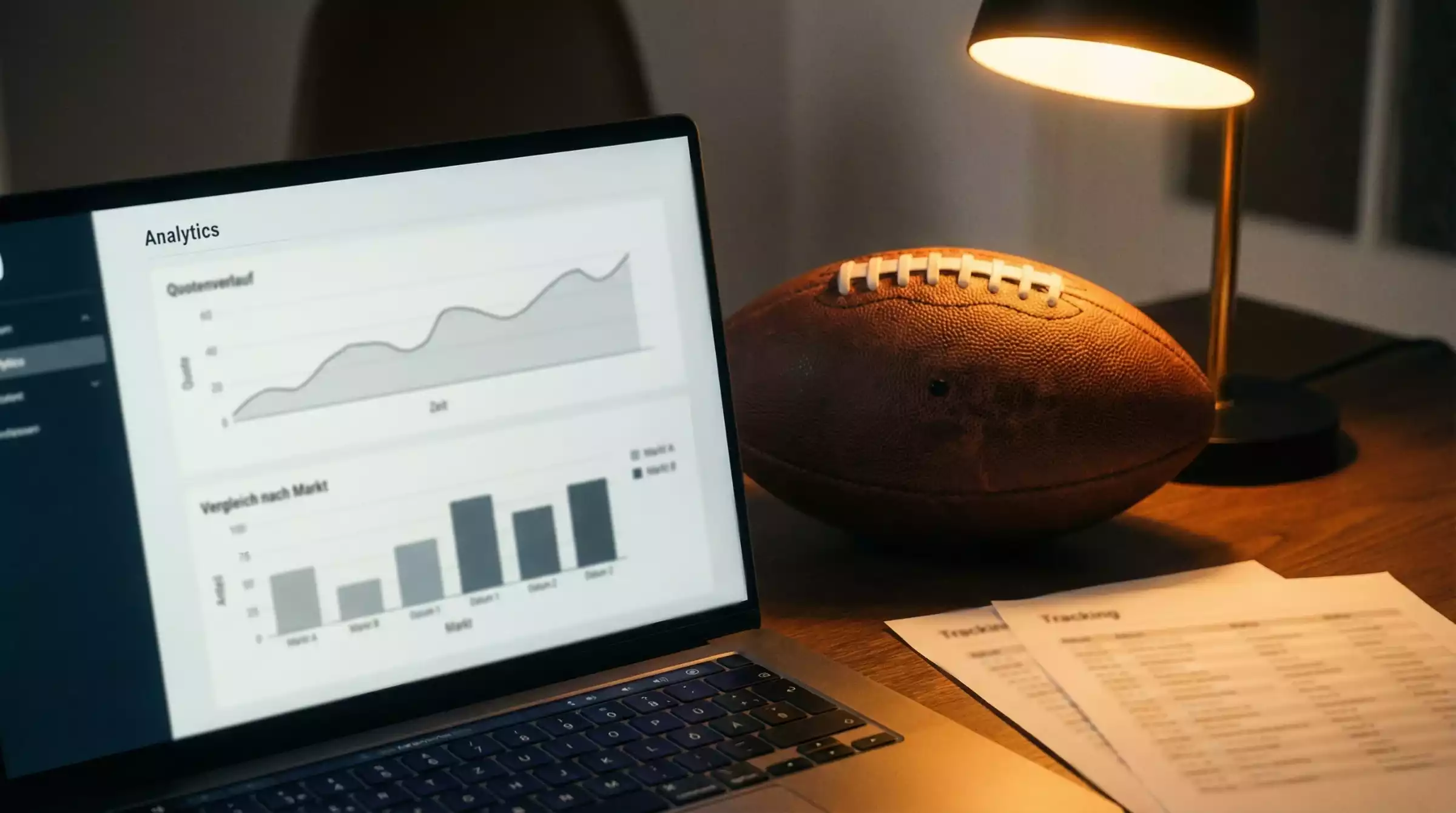 NFL Wetten Analyse — Laptop mit Statistik-Diagrammen neben einem Football auf dem Schreibtisch
